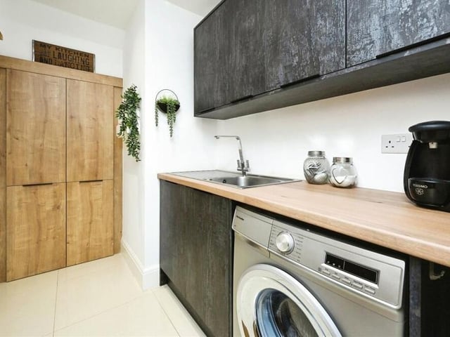 Just off the kitchen is this convenient utility room, which has space for a washing machine. It also contains base and wall-mounted units, rolled-edge work surfaces, an inset stainless steel sink with mixer tap, large storage cupboard and tiled floor.