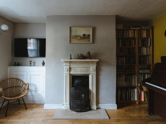 The sitting room is arranged around an open fireplace from the Regency era. It has an ornate surround, referencing classical swags and urns.