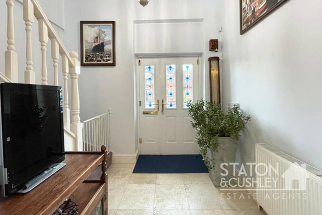 The front door opens into this grand entrance hall, which boasts a travertine marble floor and two storage cupboards.