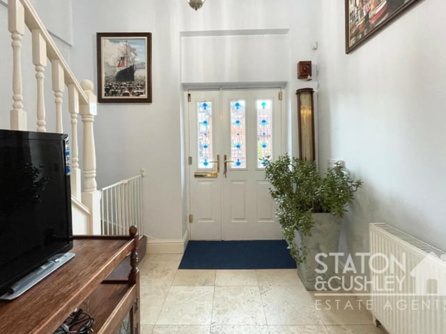 The front door opens into this grand entrance hall, which boasts a travertine marble floor and two storage cupboards.