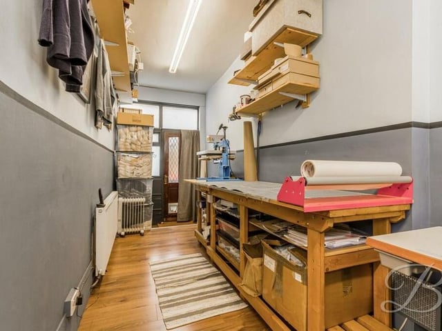 A second look at the workshop, which has access from the front and rear of the house, as well as double windows, laminate flooring and a central heating radiator.