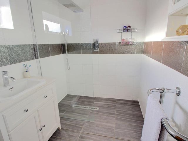 Also to be found on the first floor is this spacious bathroom, which is fully tiled and features a large and modern walk-in shower, as well as a wash hand basin and WC.