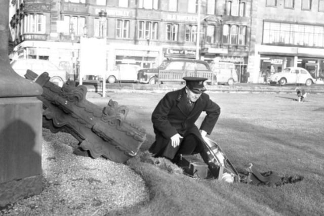 A policeman inspects the damage to Princes Street Gardens after a floodlight and stonework are dislodged from the Scott Monument by the January gales in 1968.
