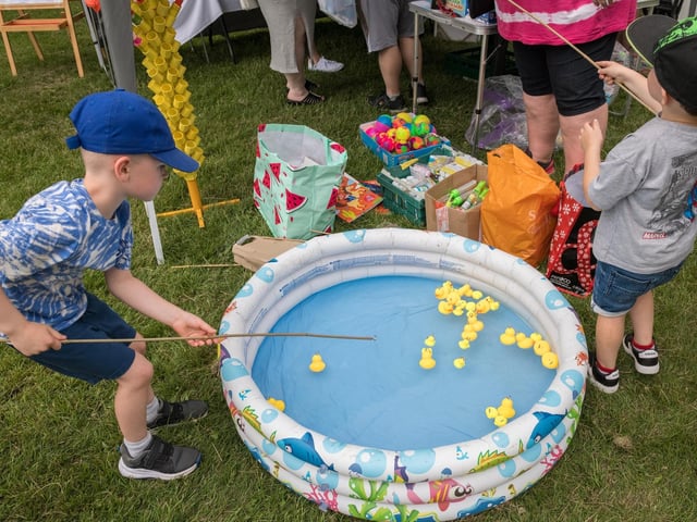 Children trying their luck at a game of hook-a-duck.