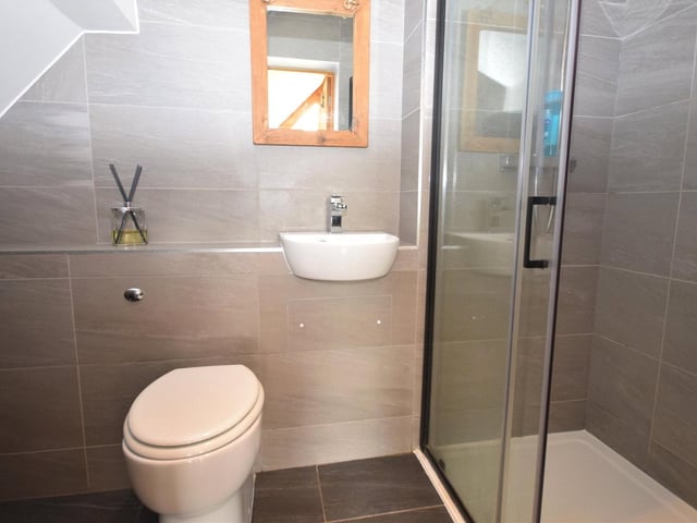 Another asset that the principal bedroom possesses is this swanky en suite shower room. It comprises a walk-in shower cubicle with rainfall shower and hand-held shower, low-flush WC and wash basin. Tiled flooring, tiled walls and underfloor heating add to its appeal.