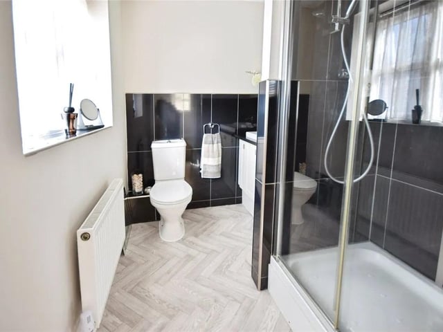 The en suite features a shower cubical, low flush W/C, vanity unit with inset sink, part tiled walls & a upvc double glazed window.