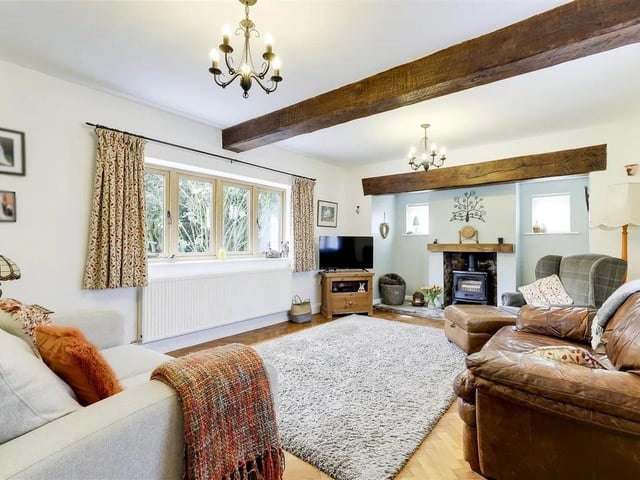 The cosy living room boasts an impressive inglenook fireplace housing a log burner, exposed wooden ceiling beams and Parquet flooring.