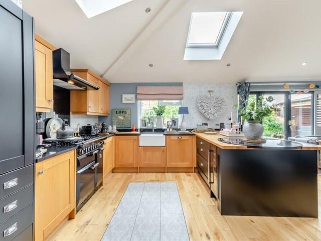 The open-plan extension is dominated by a bespoke kitchen featuring beautifully appointed, contemporary, hand-made solid oak shaker cabinetry, painted in matte black and comprising wall cupboards, base units and drawers, complemented by hand-made solid oak worktops and an inset ceramic Belfast sink with chrome oyster mixed tap and drainer.