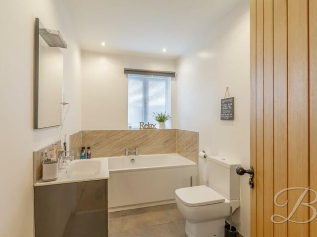 The family bathroom is fitted with a panelled bath, low-flush WC, wash hand basin with vanity storage and downlights.
