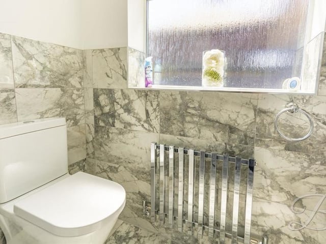 A chrome central-heating radiator is the eyecatching feature of the downstairs toilet, which also parades marble tiling. It comes complete with a low-flush WC and a vanity hand wash basin.