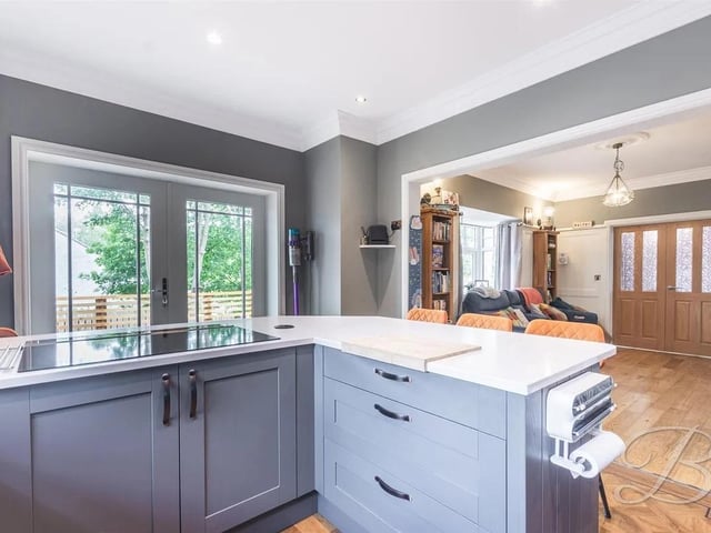 The kitchen is complete with a range of matching cabinetry, ample worktop space, a central breakfast bar, and integrated appliances.