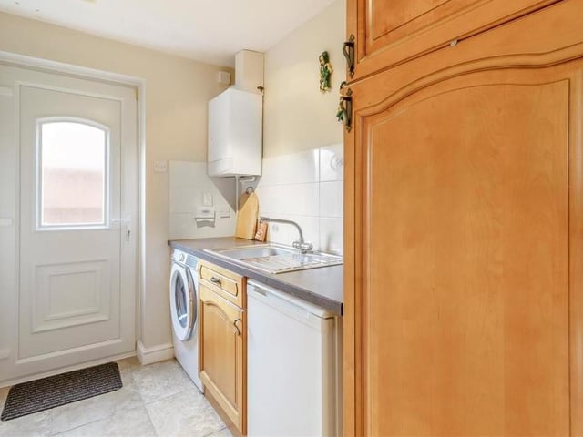 Just off the breakfast kitchen is this utility room, which has plumbing for a washing machine and space for a fridge. It also houses a wall-mounted, gas-fired central heating boiler, plus wall and base units, work surfaces and an inset stainless steel sink with drainer and mixer tap.