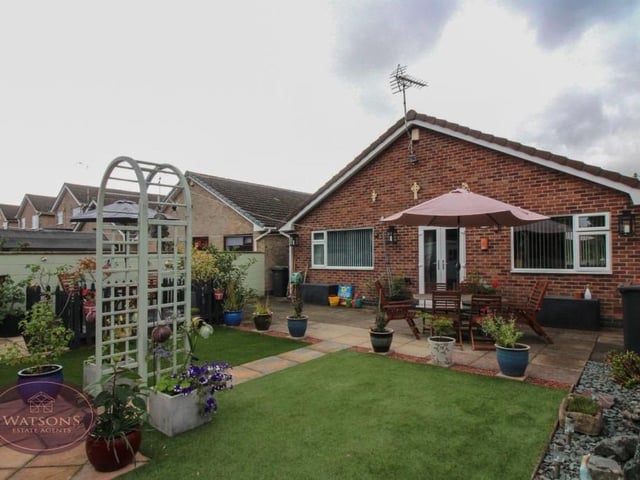 The rear garden consists of a paved patio, terrace, artificial lawn, slate borders, decorative plants and shrubs, and fencing to the perimeter.