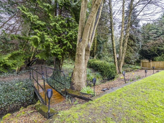 Beyond the rear garden is this footbridge, over a stream, that leads to enchanting woodland. It invites exploration with the kids, and connects the property to nature.