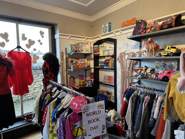 The shop has multiple rooms stocked with items, including a corner for children's books, toys, and clothing.
