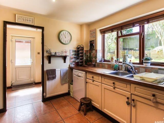 The other side of the bright and functional kitchen. It features an inset stainless steel sink and drainer.