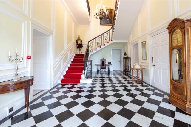 Impressive reception hall with black and white tiled floor and main staircase leading to a gallery landing.