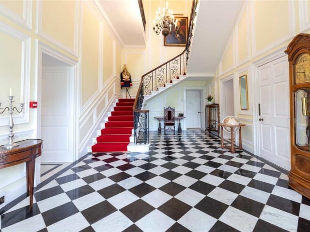 Impressive reception hall with black and white tiled floor and main staircase leading to a gallery landing.