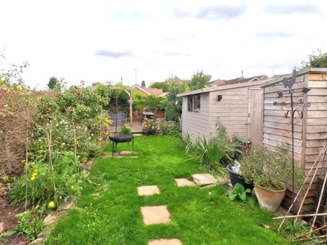 A close-up of the storage sheds and also the flower and shrub borders that extend the length of the garden.