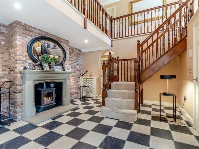 As you step into the £1.2 million Ravenshead property, you are greeted by this magnificent reception hall, with its full-height vaulted ceiling exposure to the first-floor's galleried landing. There is a stone fireplace, with inset gas fire, set against an exposed brick wall, a tiled floor and stylish staircase.