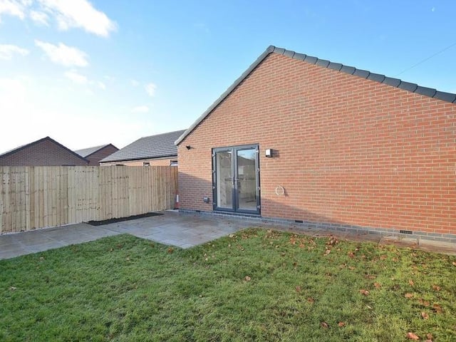 The French doors in the kitchen/diner lead out to this garden at the side of the bungalow. It is mainly laid to lawn, with an Indian sandstone patio and path too.