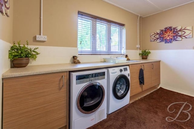 A handy utility room has space and plumbing for a washing machine and a tumble dryer. It also houses cabinets offering plentiful storage, a work surface and inset sink and drainer.
