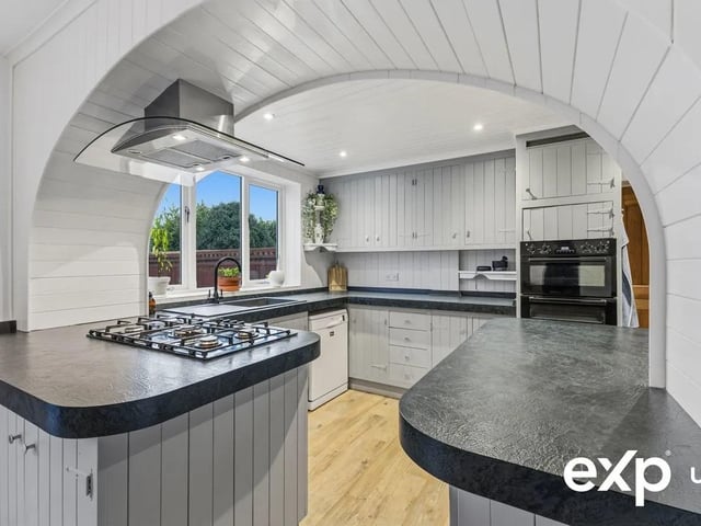 The kitchen is fitted with numerous banks of wall and base units providing considerable storage with ample worktop inset with sink and drainer, the worktops extending into a breakfast bar offering further relaxed kitchen dining. There is plumbing for a dishwasher, and appliances include an integral oven and grill and a five-ring gas hob with extractor above.