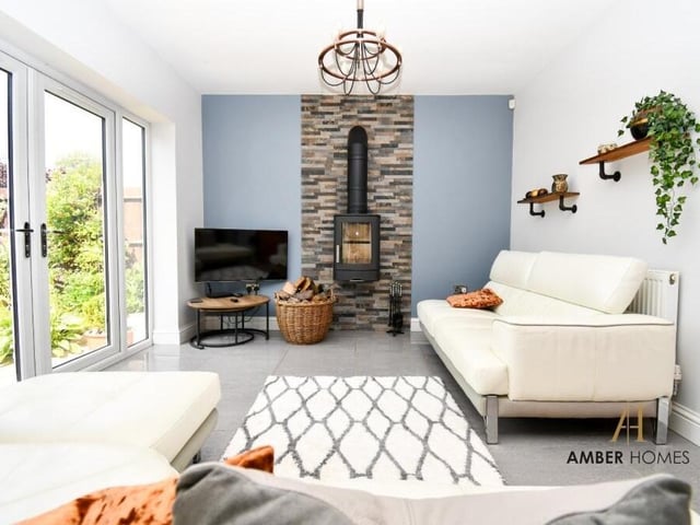 Attached to the kitchen on the lower floor is this living area, which provides a touch of luxury, especially with its wall-mounted log-burner and doors that lead outside.