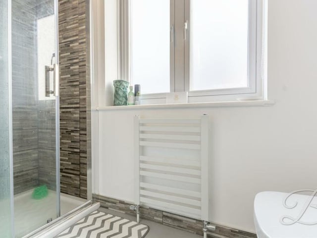 Here is the polished en suite shower room that is accessed from the second bedroom. As well as an enclosed shower, it contains a low-flush WC, wash hand basin, heated towel-rail and opaque window to the side of the house.