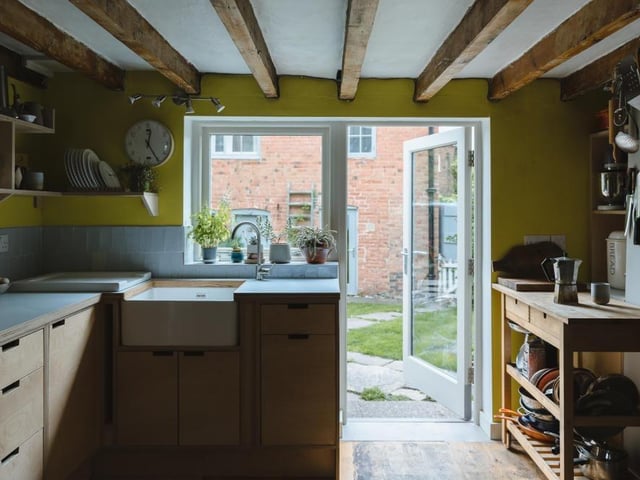 The kitchen is bespoke and constructed of laminated ply. White, hand-cut tiles reflect light and form a splashback, while the walls are painted in chartreuse, adding a vibrant and sunny pop of colour.