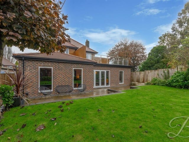 Time to have a look outside now, starting with this view of the rear of the property from the garden lawn. You can see a patio seating area and also the impressive balcony.