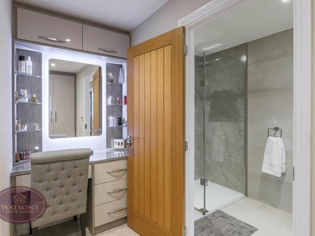 By the dressing table in the dressing room, a large oak door opens into the en suite, with shower cubicle and rainfall shower.