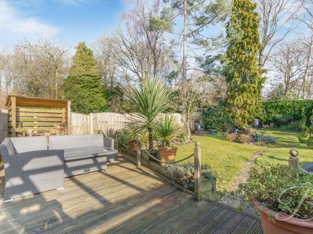 A second shot of the decked seating area, which allows you to relax and look out over the greenery of the back garden, with its lawn, trees and shrubs.