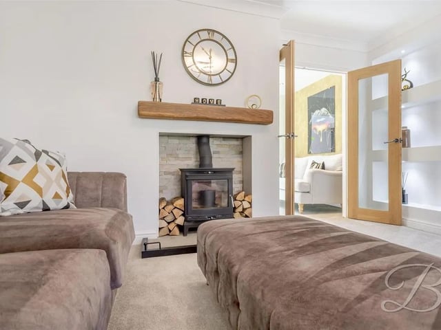 The living room features a cosy log burner fireplace and is complemented by double doors leading through to the dining area.