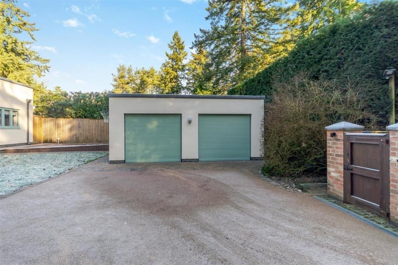 A head-on view of the block-paved driveway and the double garage, which has remote-controlled, electric roller doors. Inside the garage, there is a range of fitted base and wall units, a worktop and space for both a washing machine and a tumble dryer.