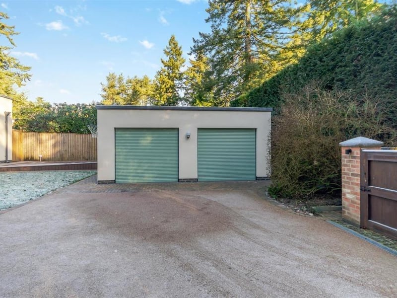 A head-on view of the block-paved driveway and the double garage, which has remote-controlled, electric roller doors. Inside the garage, there is a range of fitted base and wall units, a worktop and space for both a washing machine and a tumble dryer.
