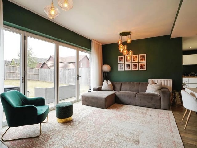 Floor-to-ceiling bi-folding glass doors fill the room with natural light and open directly onto the garden patio, creating an inviting space for relaxing or entertaining.