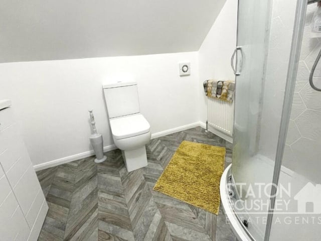 Each of the three bedrooms on the first floor has access to an en suite shower room. Here is one of them, complete with a shower cubicle, vanity unit with sink, and low-level WC.