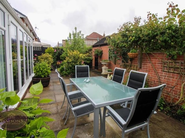 Let's step outside now and into the predominantly paved garden at the back, which is south-west facing, with flowerbed borders. It is low maintenance and has space, by the conservatory, for this pleasant seating area.