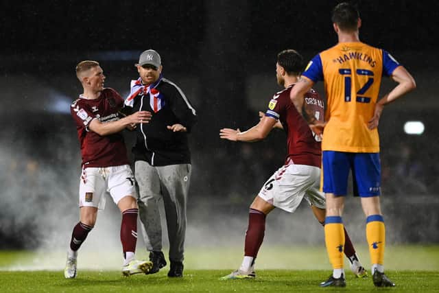 A pitch invader is stopped by Fraser Horsfall of Northampton Town as he runs towards Stags' Oli Hawkins near the end of the semi-final.