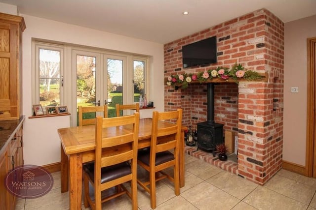 An inglenook fireplace with inset gas stove creates a cosy corner in the dining kitchen, where there is space for a breakfast table. French doors lead to the back garden.