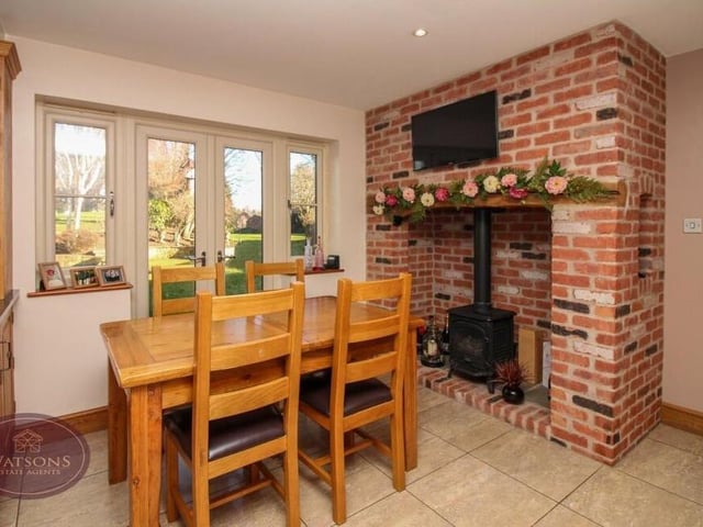 An inglenook fireplace with inset gas stove creates a cosy corner in the dining kitchen, where there is space for a breakfast table. French doors lead to the back garden.