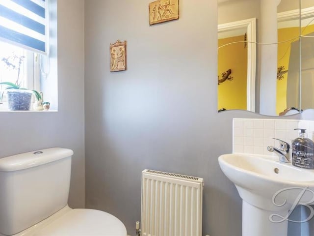 This is the downstairs toilet, off the entrance hallway. It comprises a low-flush WC, pedestal sink, central heating radiator and opaque window to the front of the house.