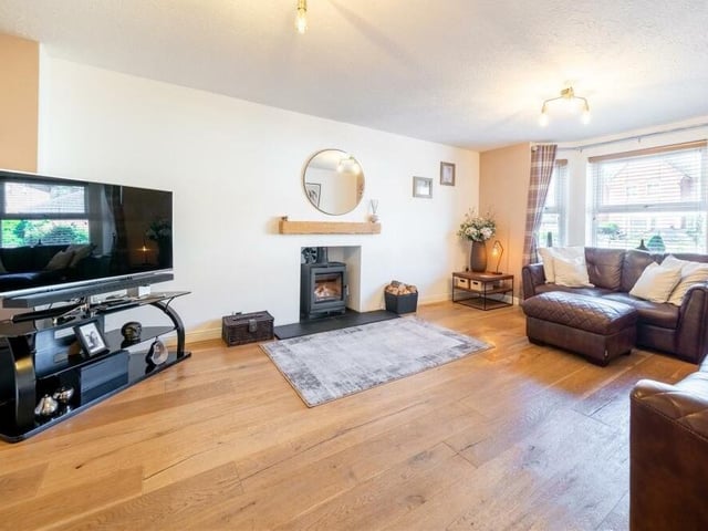 The ground floor hosts two reception rooms, including this family lounge or living room, with a bay window facing the front of the house and a feature fireplace with log-burning stove.