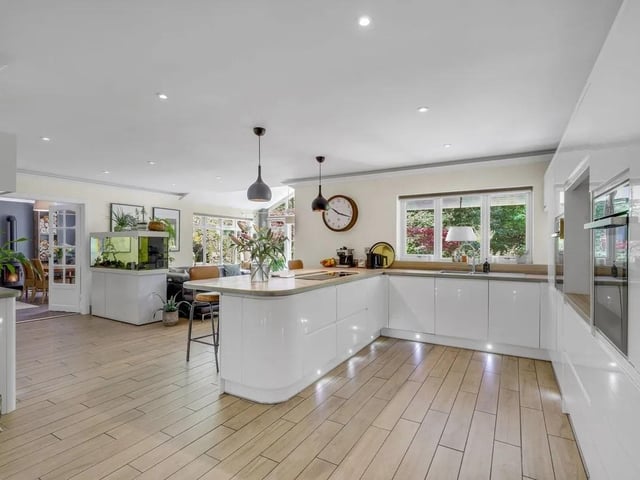 The fitted kitchen features a breakfast bar, integrated neff appliances include a dishwasher, a 90cm induction hob with a downdraft extractor, two pyrolytic self-cleaning hide-and-slide ovens, a combi microwave oven, while further integrated appliances include an AEG washer/dryer, fridge and freezer.