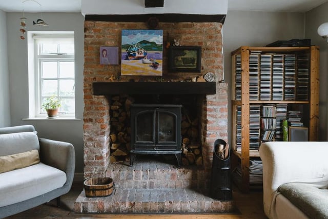 A wood-burning stove, within an exposed brick hearth, forms the focal point of the sitting area in the open-plan living room.