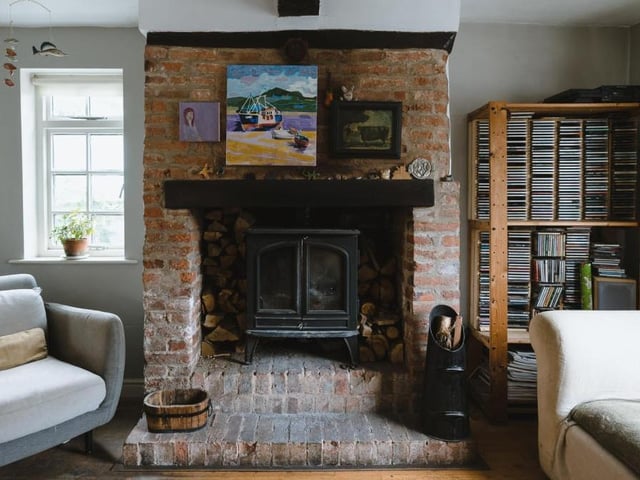 A wood-burning stove, within an exposed brick hearth, forms the focal point of the sitting area in the open-plan living room.
