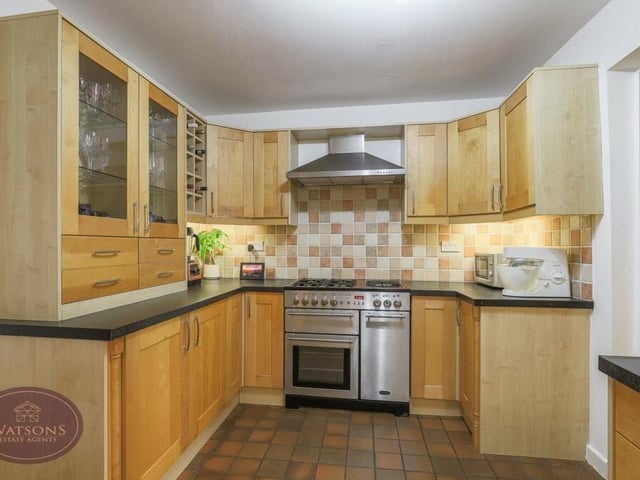 Integrated appliances within the kitchen/diner include a dishwasher and fridge, while there is space for a range-style cooker with extractor over. The floor is tiled.