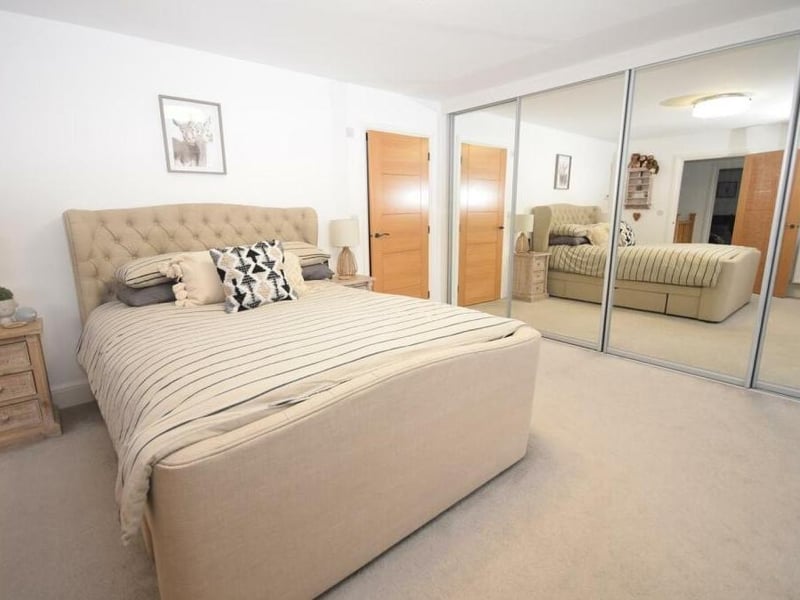 The first of five bedrooms we look at is the master, a lovely, large space with a range of fitted, mirrored wardrobes that add a bespoke, boutique feel to the room. It faces the front of the house and has access to an en suite shower room.