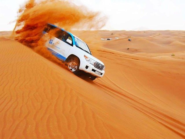 Experience the red dunes of Dubai's Lahbab desert and enjoy activities like sandboarding, 4WD dune bash, camel riding, falcon interaction and more before enjoying a BBQ buffet dinner and live show. By OceanAir Travels.